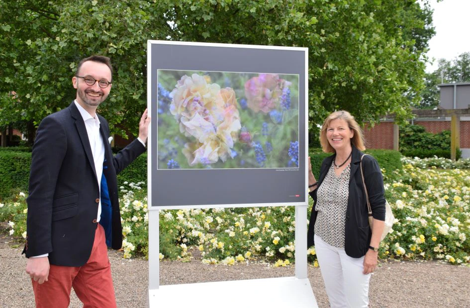 Alexander Linke und eine Frau stehen vor einer Infotafel, die Blumen zeigt.