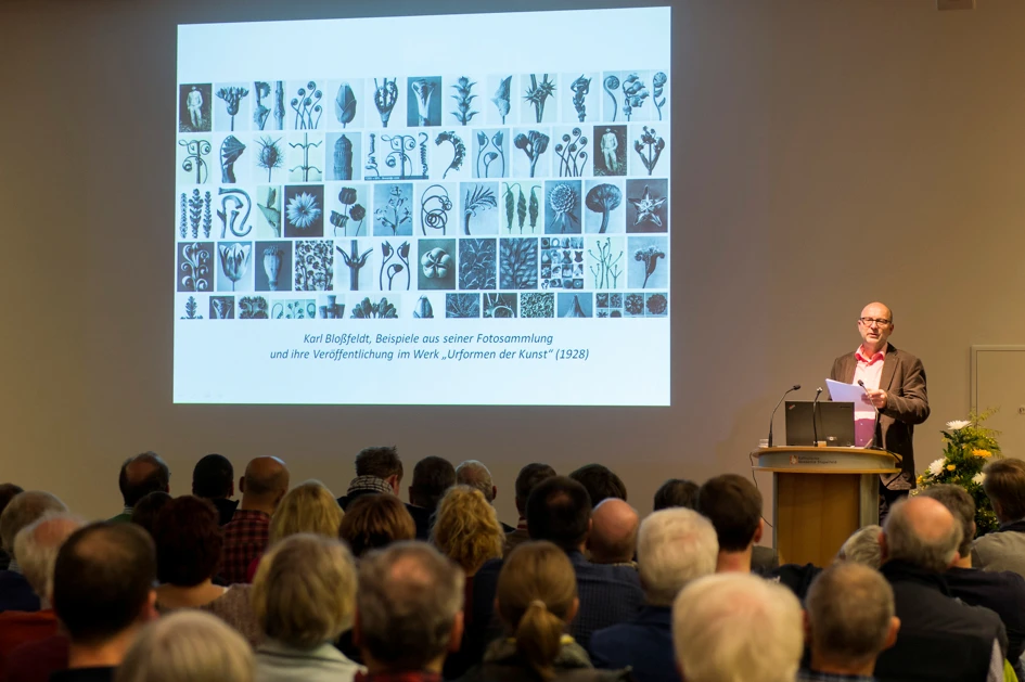 Ein Mann hält in einem Raum der Katholischen Akademie Stapelfeld einen Vortrag vor einer Menschengruppe.