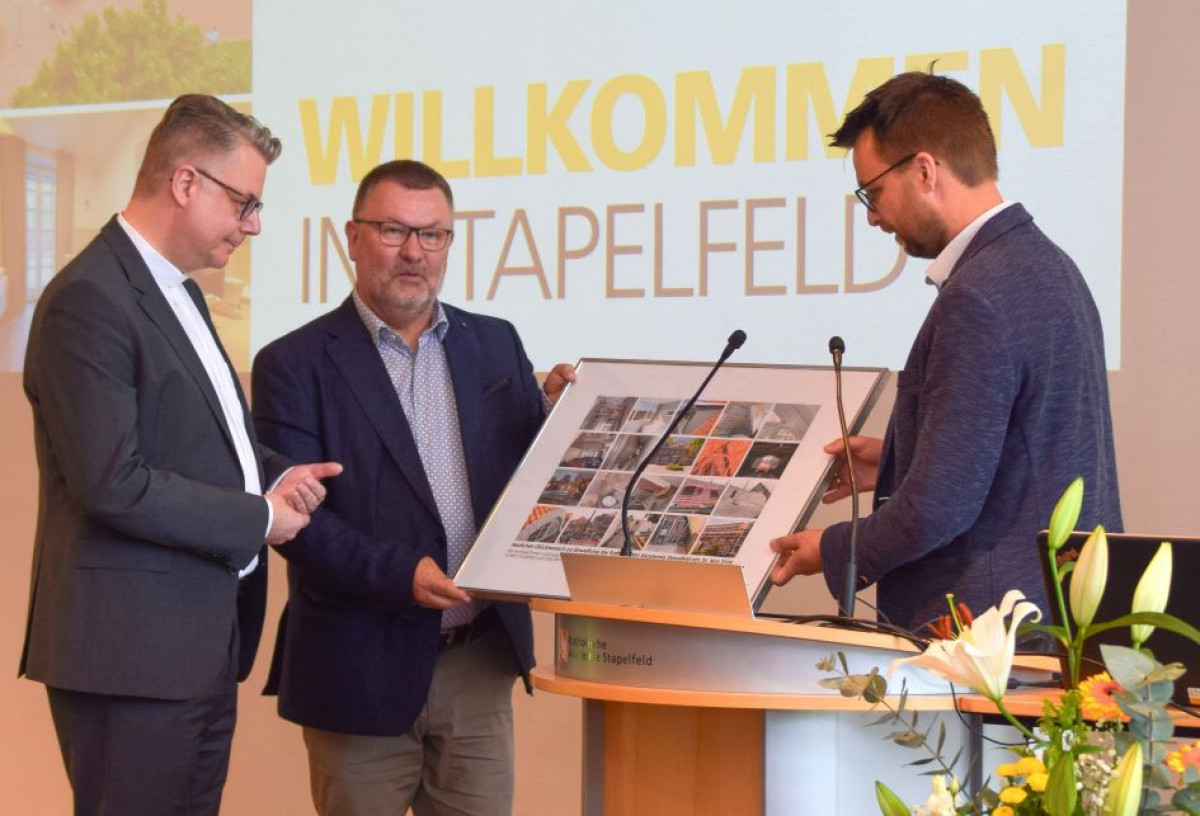 Architekt Nils Jarecki-Köhne (rechts) überreicht eine Bildcollage der Bauphase an die Direktoren Dr. Marc Röbel (links) und Willi Rolfe