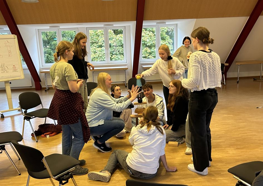 Gruppe an Schülern baut einen Turm mit verschiedenen Gegenständen